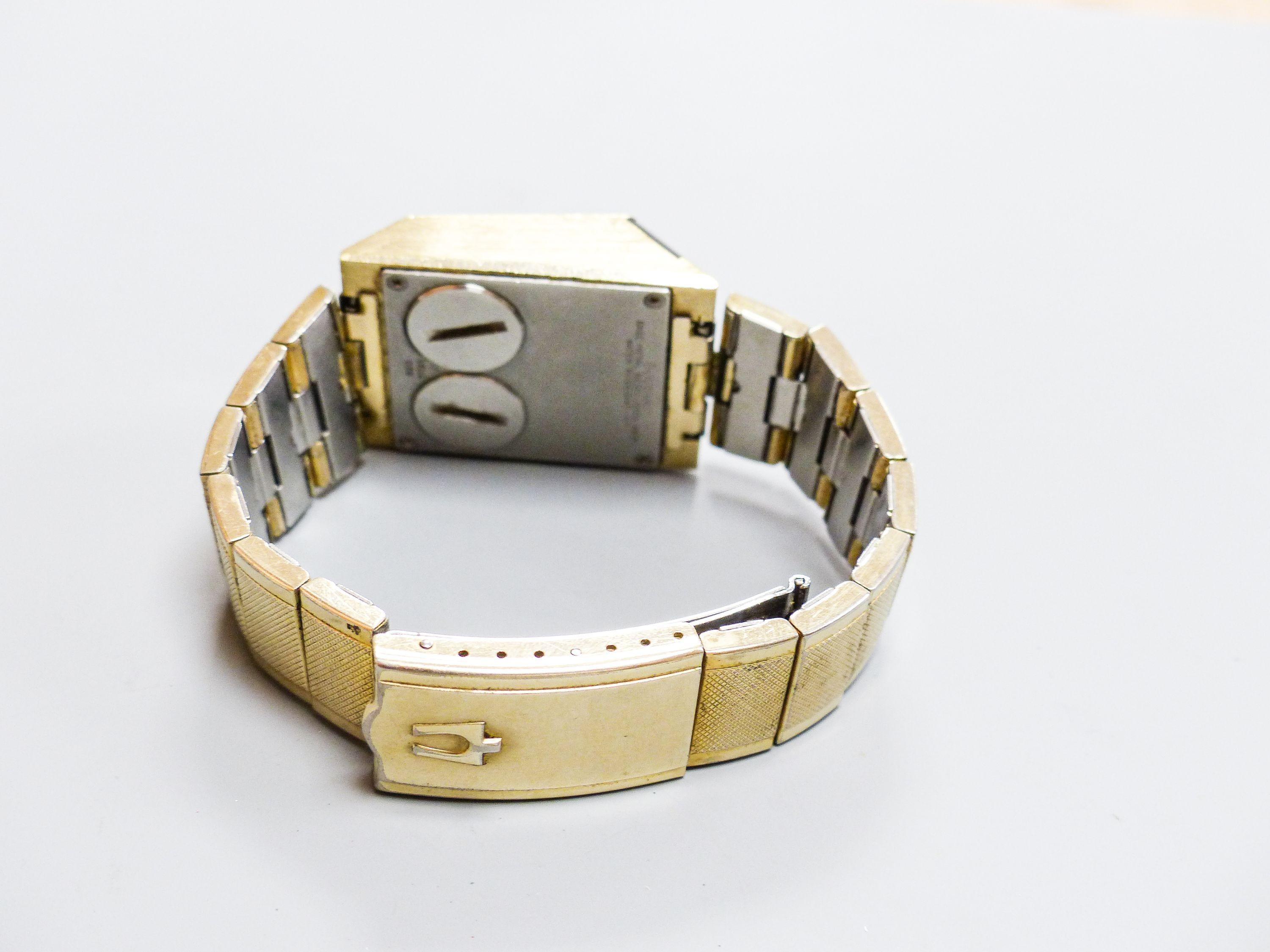 A gentleman's steel and gilt base metal Bulova digital wrist watch, on Bulova bracelet, case diameter 30mm (a.f.).